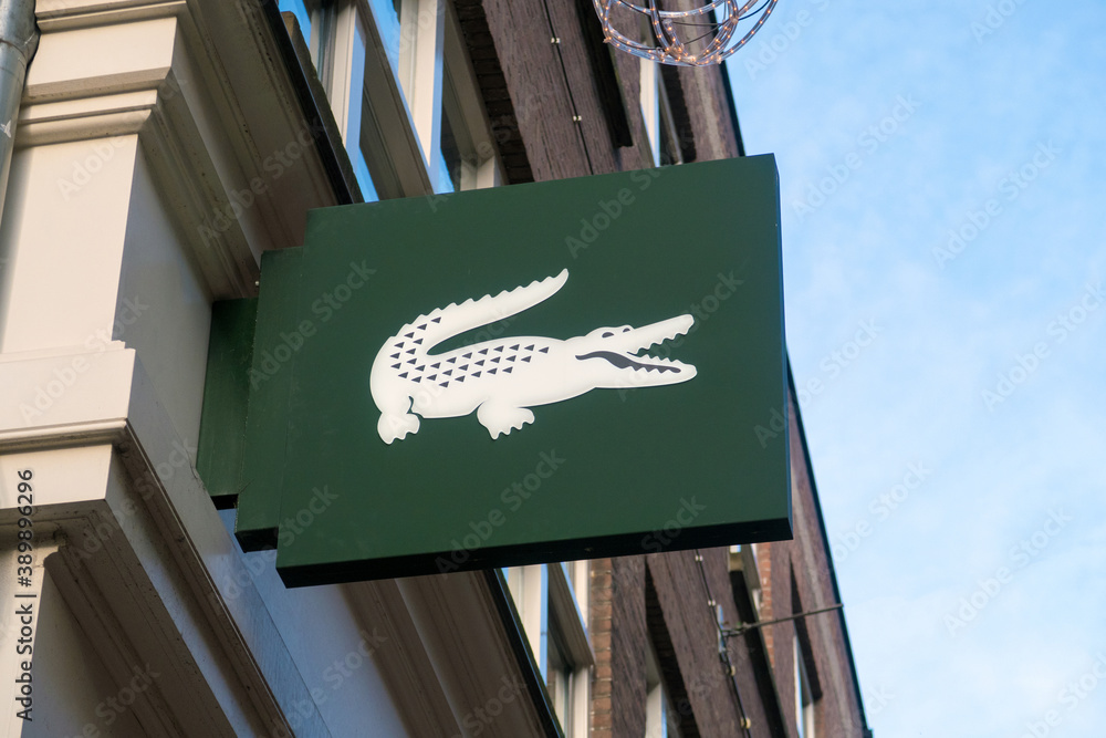 Amsterdam, The Netherlands - January 2020. crocodile logo closeup shop sign on store front. French company selling clothing, footwear, sportswear, eyewear, leather goods. Stock-foto | Adobe Stock