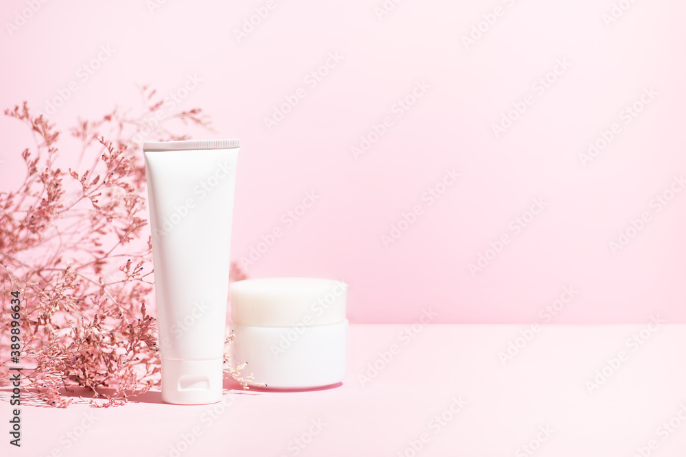 Creme tube and jar with dried flowers on the pink background with copy space for text Creme tube and jar with dried flowers on the pink background with copy space for text