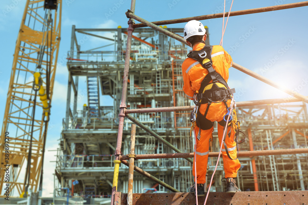 Fotografija Safety concept, worker on high at scaffolding wearing equipment protective safety harness all PPE with rope for sprinkle from high area and structrue steel in construction site background