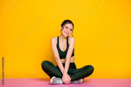 Portrait of pretty sportive cheerful shy girl doing class mat work studio isolated on bright yellow color background