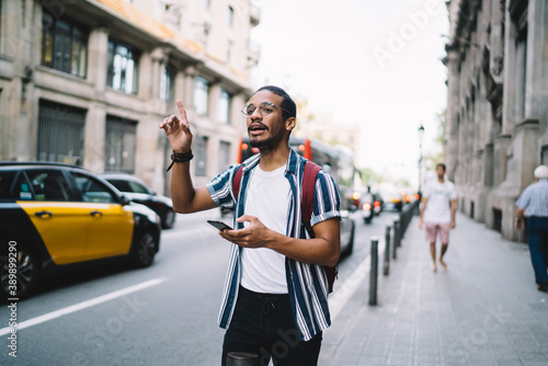 Focused man using smartphone and hailing taxi