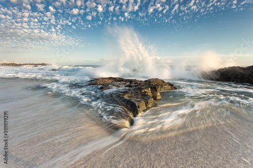 Fototapeta Naklejka Na Ścianę i Meble -  Wide angle view of a wave splashing over a big rock on blouberg beach in Cape Town in the Western Cape of South Africa