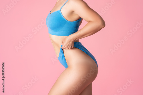 Slim sexy woman in blue underwear on pink background