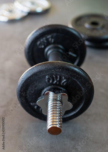 Dumbbell with 2 kg iron plates on a concrete surface and with more weight plates at the bottom