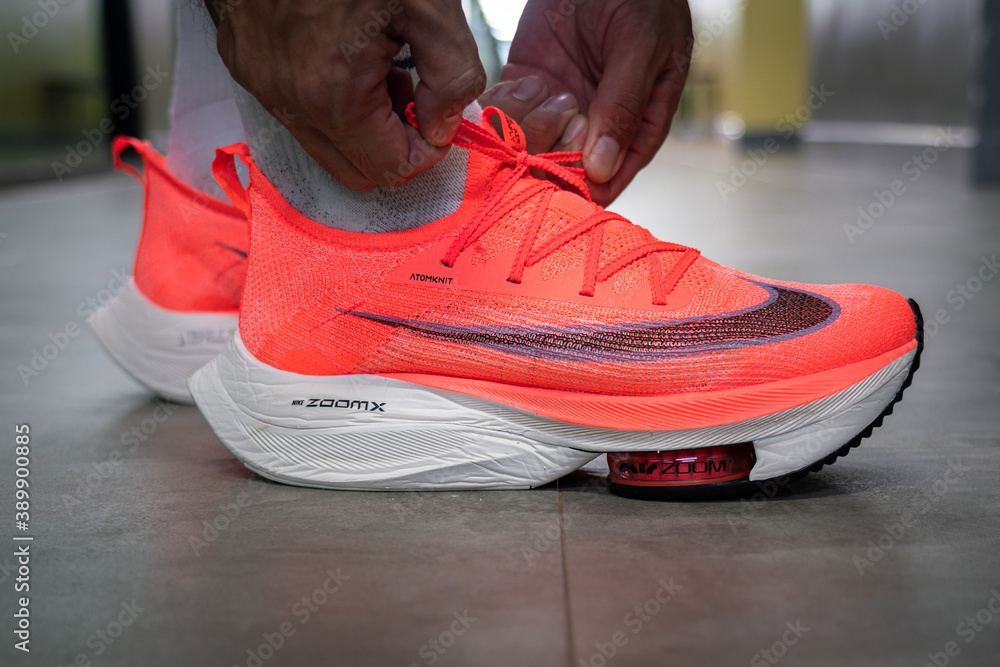 Bangkok Thailand October 2020 A runner is lacing up the new Nike Alphafly Next top most famous performance running shoes in bright orange colorway. Close up action and selective focus. Stock