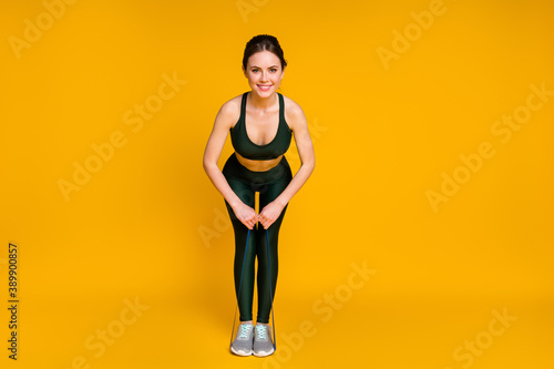 Full length photo of sporty lady stretch rubber elastic stripe arms workout wear sports suit isolated yellow color background