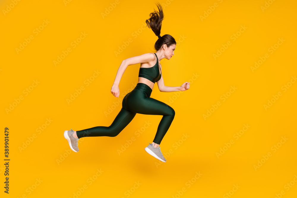 Full length profile photo of sportive lady jump high up running wear sports suit shoes isolated yellow color background