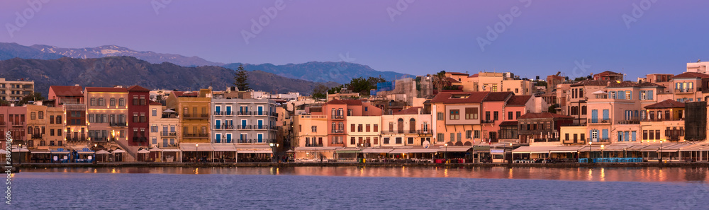 Sunrise or sunset over Old Venetian port and harbour promenade of Chania, Crete, Greece. Great purple sky, distant Cretan mountains. Panoramic shot.