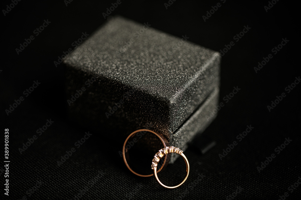 engagement wedding rings with a diamonds next to a beautiful black stylish box on a black background.
close-up of golden rings on dark background
engagement wedding rings with a diamonds next to a beautiful black stylish box on a black background.
close-up of golden rings on dark background
