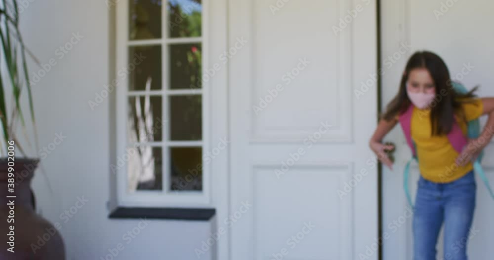 Caucasian girl wearing face mask with backpack standing outside the house Caucasian girl wearing face mask with backpack standing outside the house