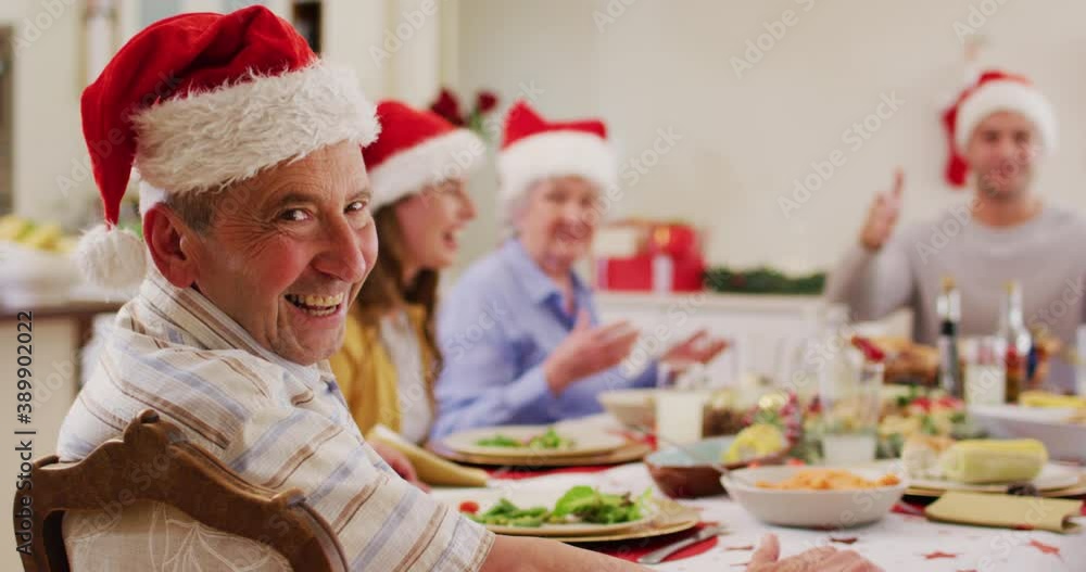 Portrait of caucasian senior man in santa hat smiling while sitting on dining table and enjoying lun Portrait of caucasian senior man in santa hat smiling while sitting on dining table and enjoying lun