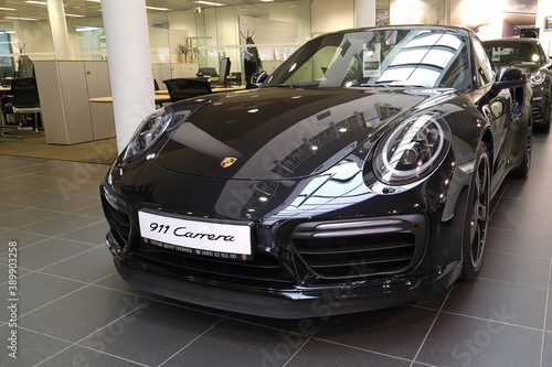Moscow. February 2018. Black Porsche 911 991 Carrera  at dealer showroom. Headlights and aerodynamic turbo packed Front and left side view