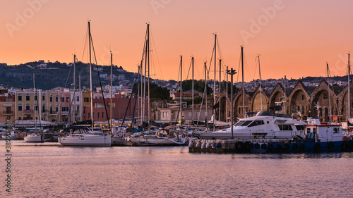 Sunrise over Old Venetian harbour of Chania, Crete, Greece. Sailing boats anchored by pier, Old Venetian shipyards or Neoria and Cretan mountains photo