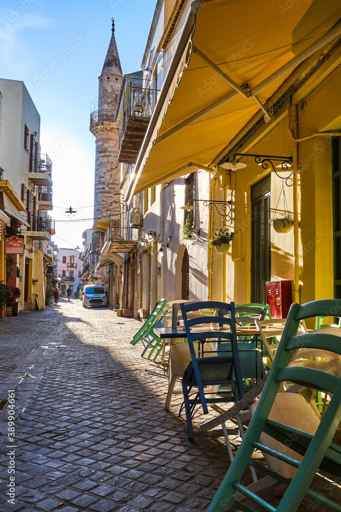 Early morning in old narrow streets of Chania, Crete, Greece and historical monument of Ottoman era - Ahmet aga minaret. Street cafes and restaurant