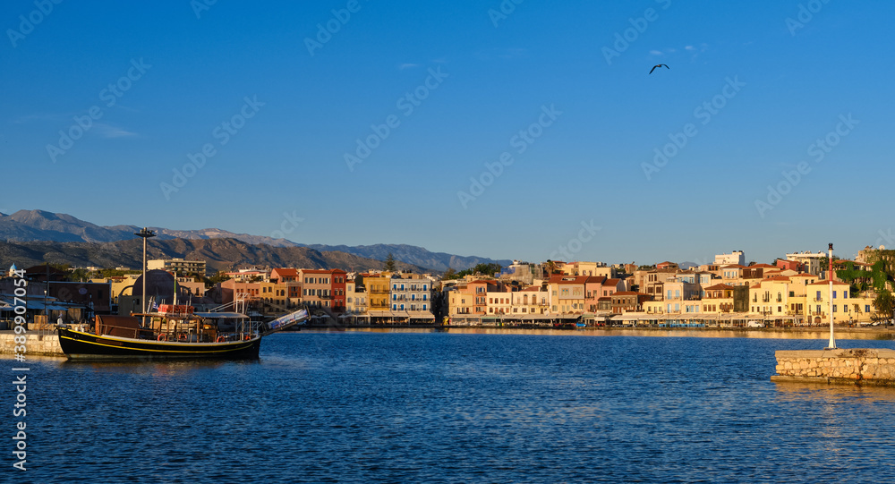 Beautiful view of Old Venetian harbour of Chania, Crete, Greece, quayside, tourist boats by piers in early morning. Cretan mountains in background.