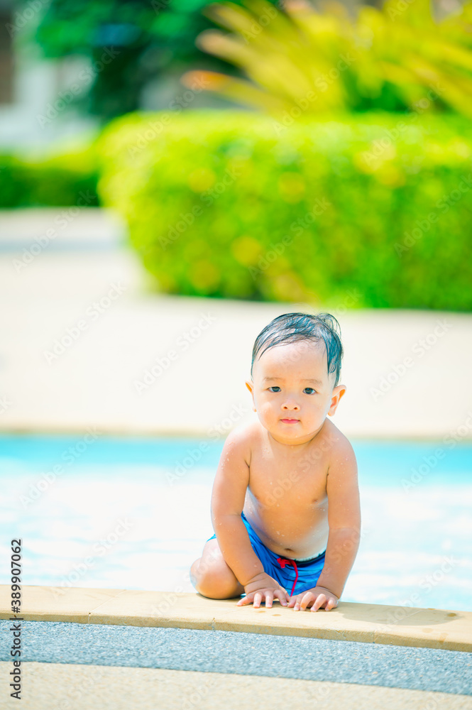 little baby boy enjoying swimming in a swimming pool in summer vacation.