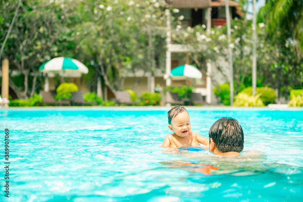 Asian father swimming with cute adorable baby in swimming pool.