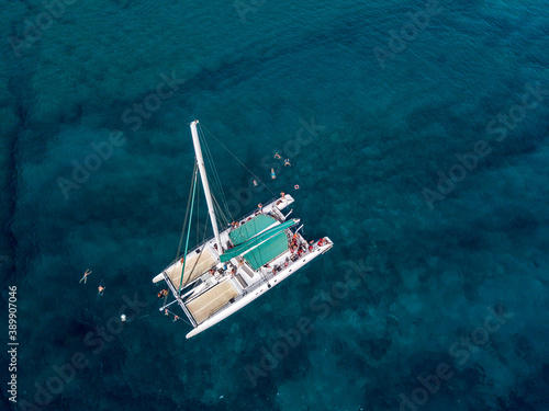 Aerial view of a catamaran with people on board and in the sea, swimming near the coasts of the island of Lanzarote, Canary, Spain. Jet ski performing in the sea  © Naeblys