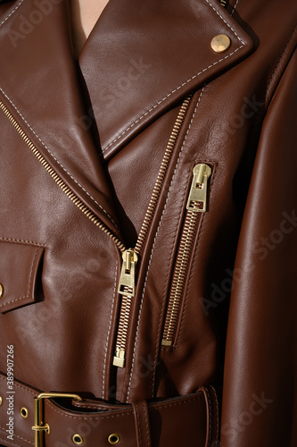 Brown leather jacket with metal zippers on it. Girl in a stylish white jacket. Stitched leather. Closeup. Vertical fashion background. © Alexander