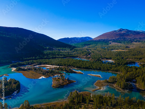 Serene mountain lake and pine forest in the wild mountains on a sunny day with clear blue skies.
