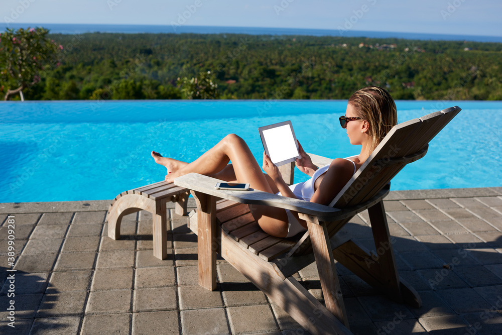 Relaxed woman using tablet near swimming pool
