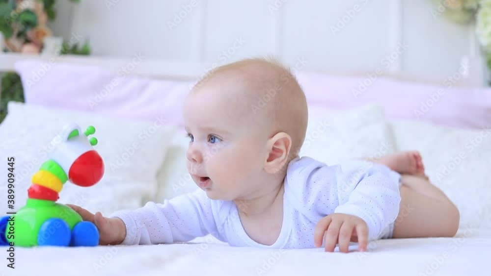 a child plays with a rattle on the bed at home a child plays with a rattle on the bed at home