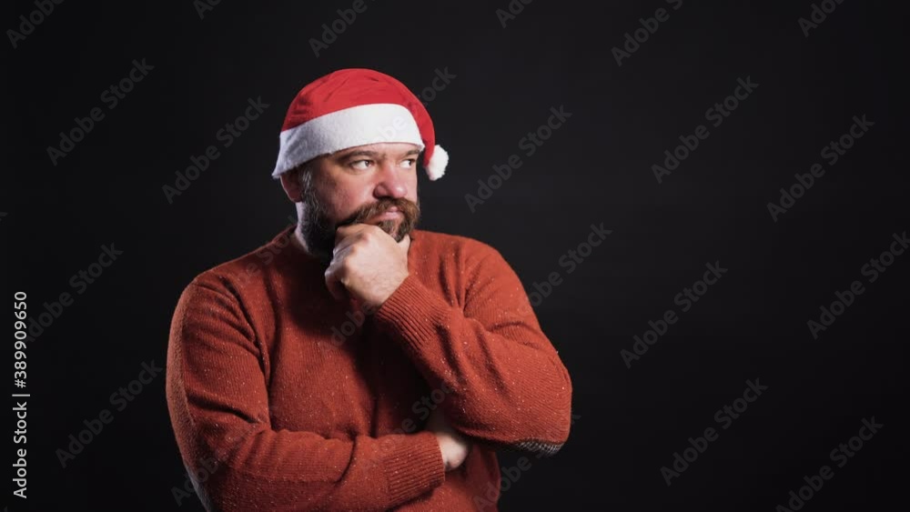 bearded man on a black background wearing a santa claus hat thinks and tries to solve the issue bearded man on a black background wearing a santa claus hat thinks and tries to solve the issue