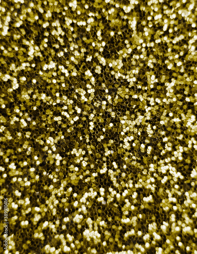 Glitter splash and lens flare on gold shiny trendy background. Sequins. Festive background for your projects. Blurred golden festive bokeh lights. Christmas festive time concept on background.