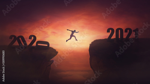 Surreal view, man jumping over a chasm obstacle between old 2020 and new 2021 years. Self overcome, starting a new life. Way to win and success, sunset sky scene. Motivational achieving goals concept.