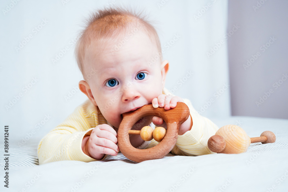 A sevenmonthold girl with blue eyes lies on her stomach in a bright