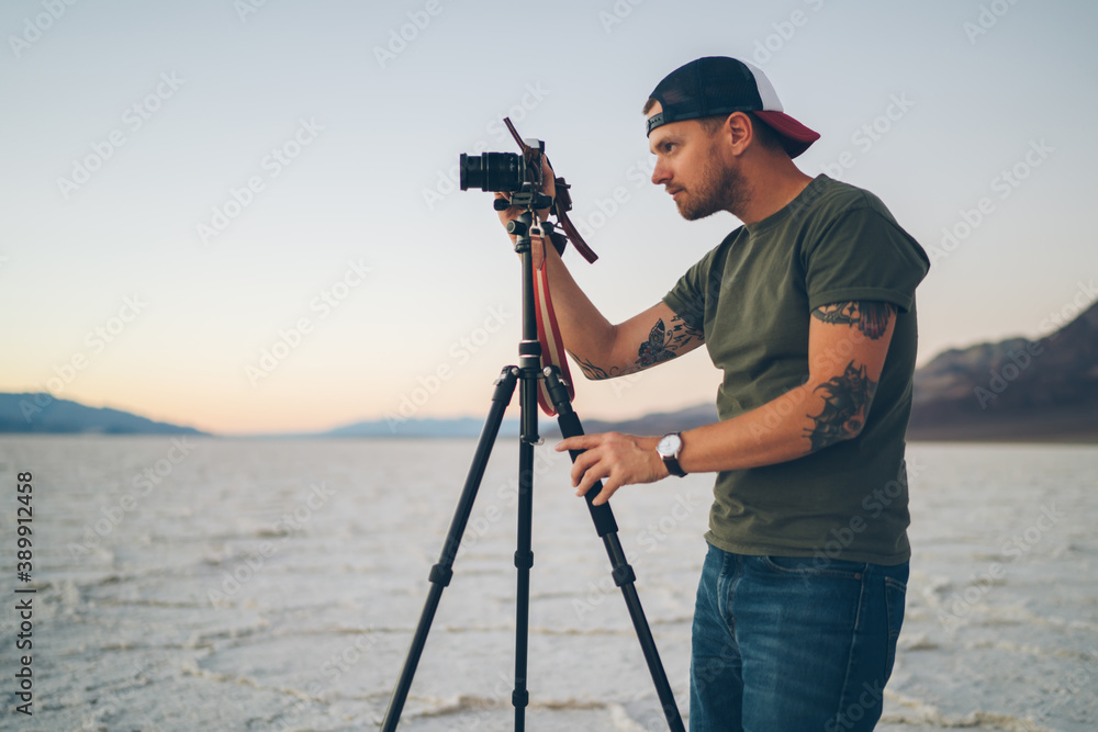 Male traveler photographing sunset in waterless terrain