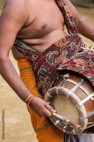 Indian man playing drum during temple festival in Kerala photo