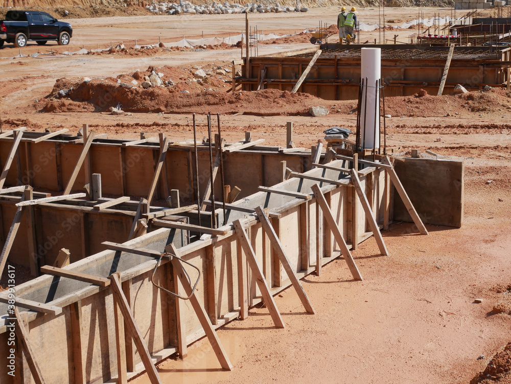 KUALA LUMPUR, MALAYSIA -MARCH 5, 2020: Building ground beam under construction using temporary timber plywood formwork at the site. Reinforced by the reinforcement steel to strengthen the structure. KUALA LUMPUR, MALAYSIA -MARCH 5, 2020: Building ground beam under construction using temporary timber plywood formwork at the site. Reinforced by the reinforcement steel to strengthen the structure.