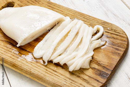 Sliced raw squid on a cutting board.