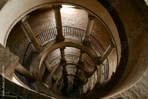 Spiral rounded ramp stairs. Into the dark, into the light. Rising up, going down. Mystic lighting. Ancient historic walls and columns.
