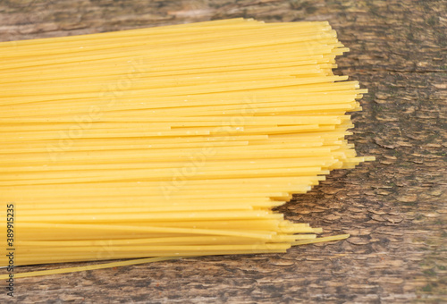 Raw spaghetti on wooden background close up
