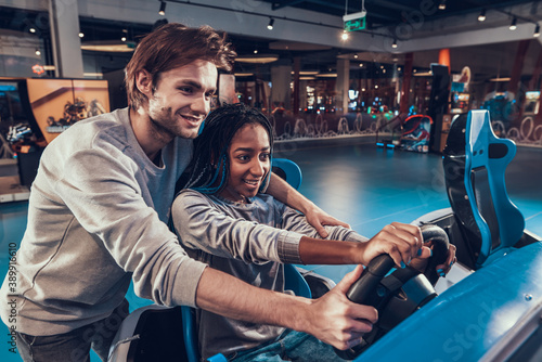 Man helping woman to drive at play center. 