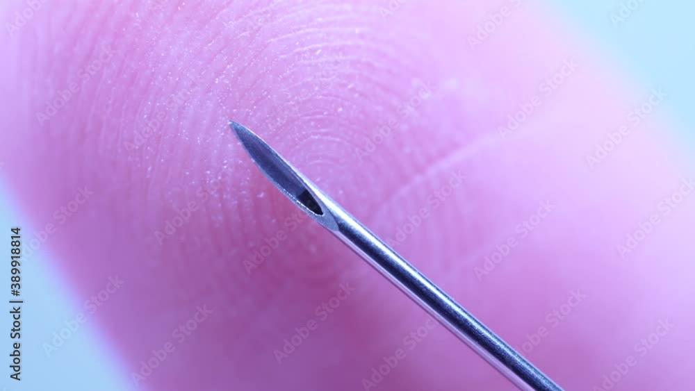 Finger touching medical syringe needle. Macro close up. Trypanophobia