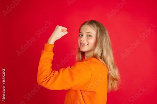 Strong, power. Portrait of young caucasian woman isolated on red studio background with copyspace. Beautiful female model. Concept of human emotions, facial expression, sales, ad, youth.