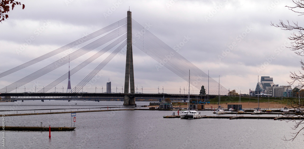 A cable-stayed bridge can be seen across the river Daugava. Before it is a marina
