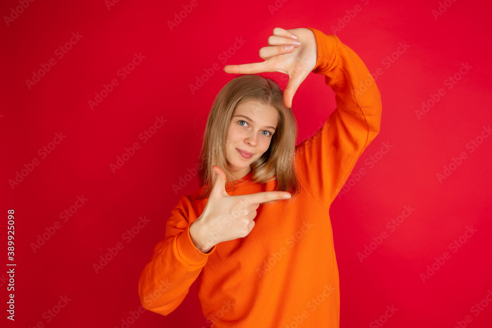 Framing face with hands. Portrait of young caucasian woman isolated on red studio background with copyspace. Beautiful female model. Concept of human emotions, facial expression, sales, ad, youth. Framing face with hands. Portrait of young caucasian woman isolated on red studio background with copyspace. Beautiful female model. Concept of human emotions, facial expression, sales, ad, youth.