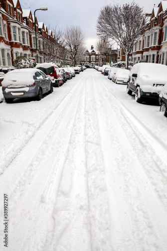 Street winter cityscape with snow terraced houses and frozen cars after a blizzard snowfall in London England UK, stock photo image with copy space