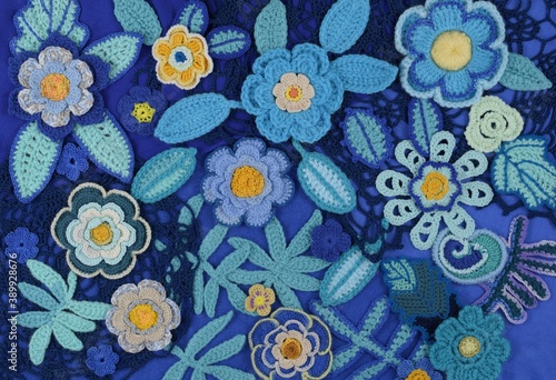 A blue floral background made from crocheted flowers and leaves.