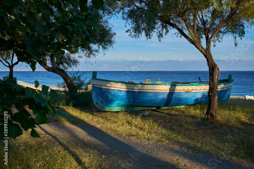 green Sicilian seafront overlooking the Messina strait with typical wooden fishing boats