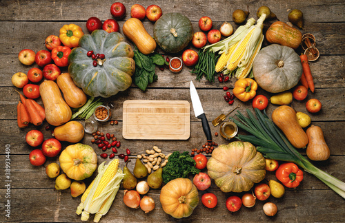 Wooden cutting board with autumn vegetables on wooden table