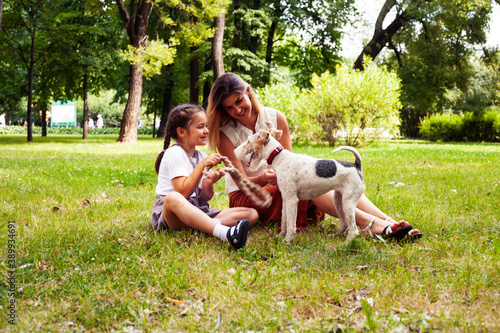 young pretty caucasian mother walking with little cute daughter and dog fox terrier, lifestyle people concept © iordani