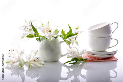 Graceful white flowers and coffee set on a glossy background. Alstrameria, two cups and a milk jug. Still life