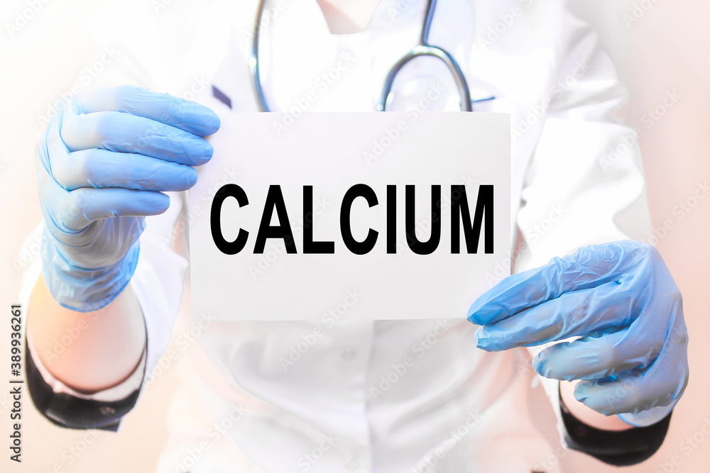 The doctor's blue - gloved hands show the word CALCIUM - . a gloved hand on a white background. Medical concept. the medicine The doctor's blue - gloved hands show the word CALCIUM - . a gloved hand on a white background. Medical concept. the medicine