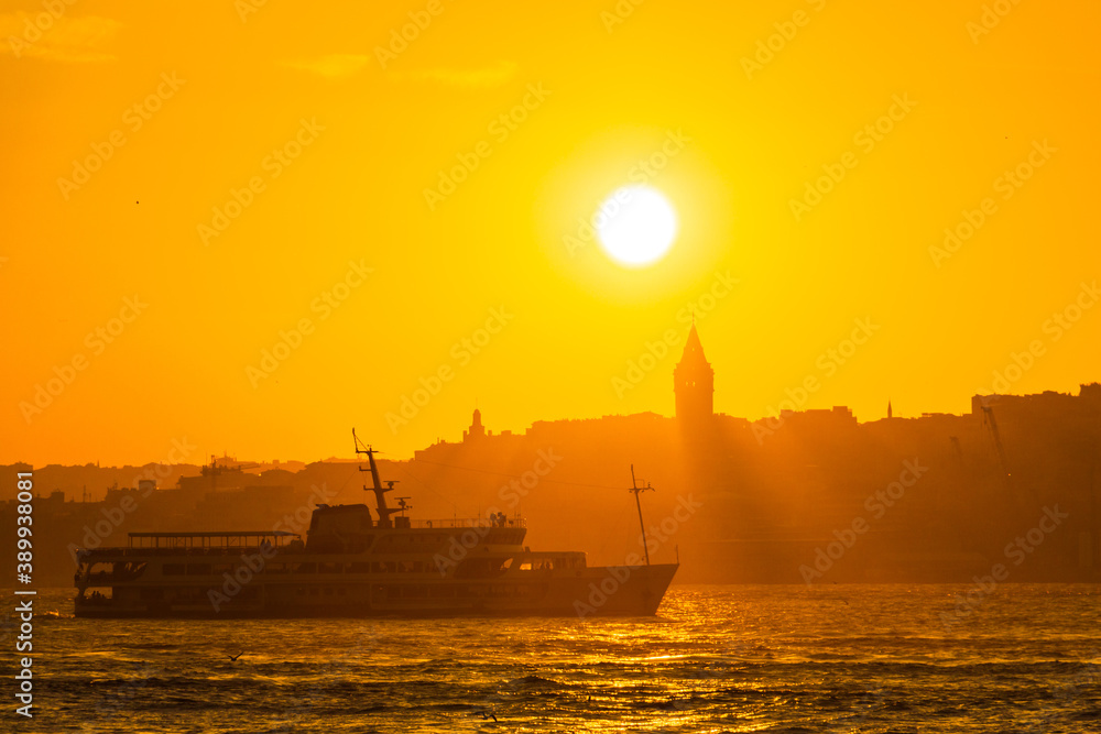 Galata Tower at sunset. Sun over the Galata Tower. Cityscape of Istanbul with Galata Tower at sunset. Galata Tower and a ferry