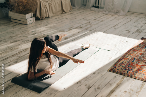 Beautiful brunette fitness woman make stretching exercises, doing yoga indoors at home. Staying fit and healthy photo